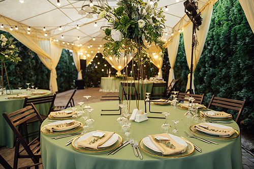 Backyard wedding rentals like tables, chairs, lighting, and a tent set up for a backyard wedding